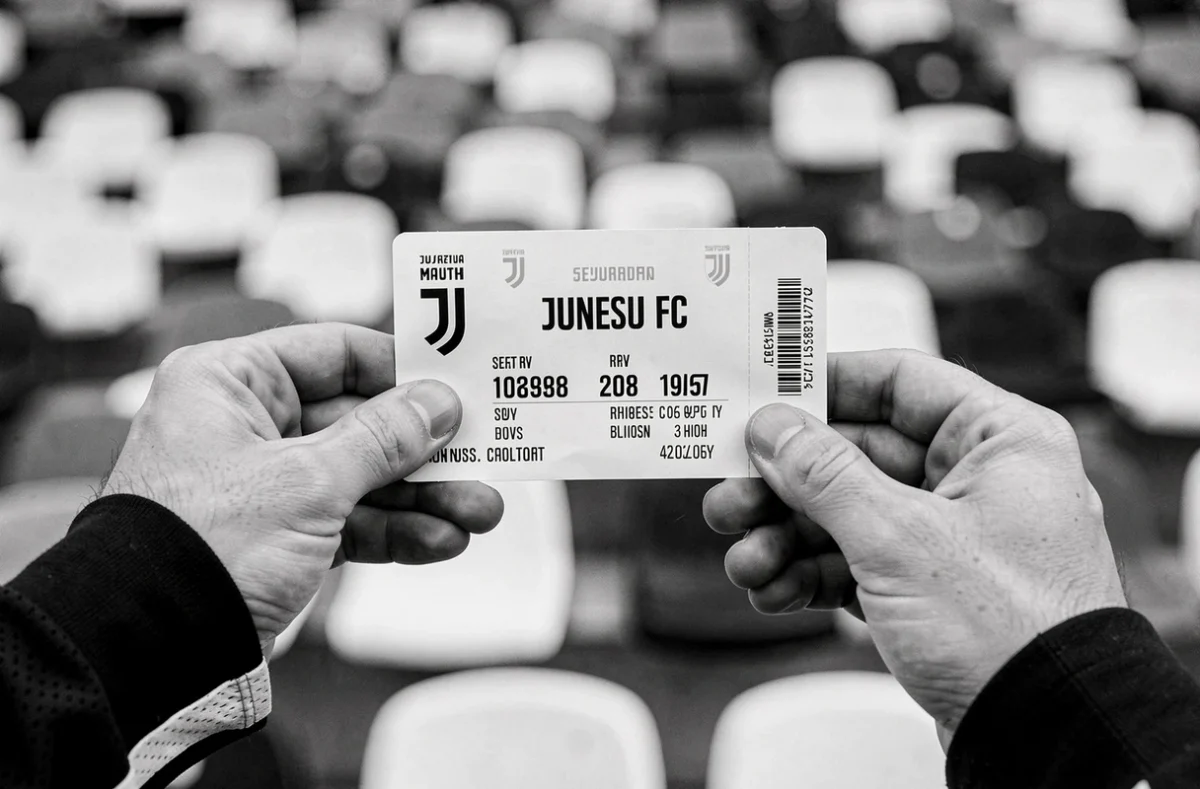 Gros plan sur un billet physique de match de la Juventus FC avec gradins du stade en arrière-plan