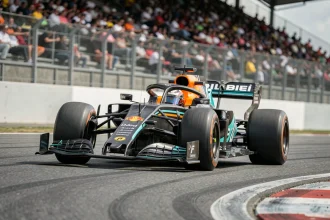 Monoplace de Formule 1 en plein virage sur circuit, vue en contre-plongée au niveau de la piste, illustrant la compétition serrée du championnat F1 2026